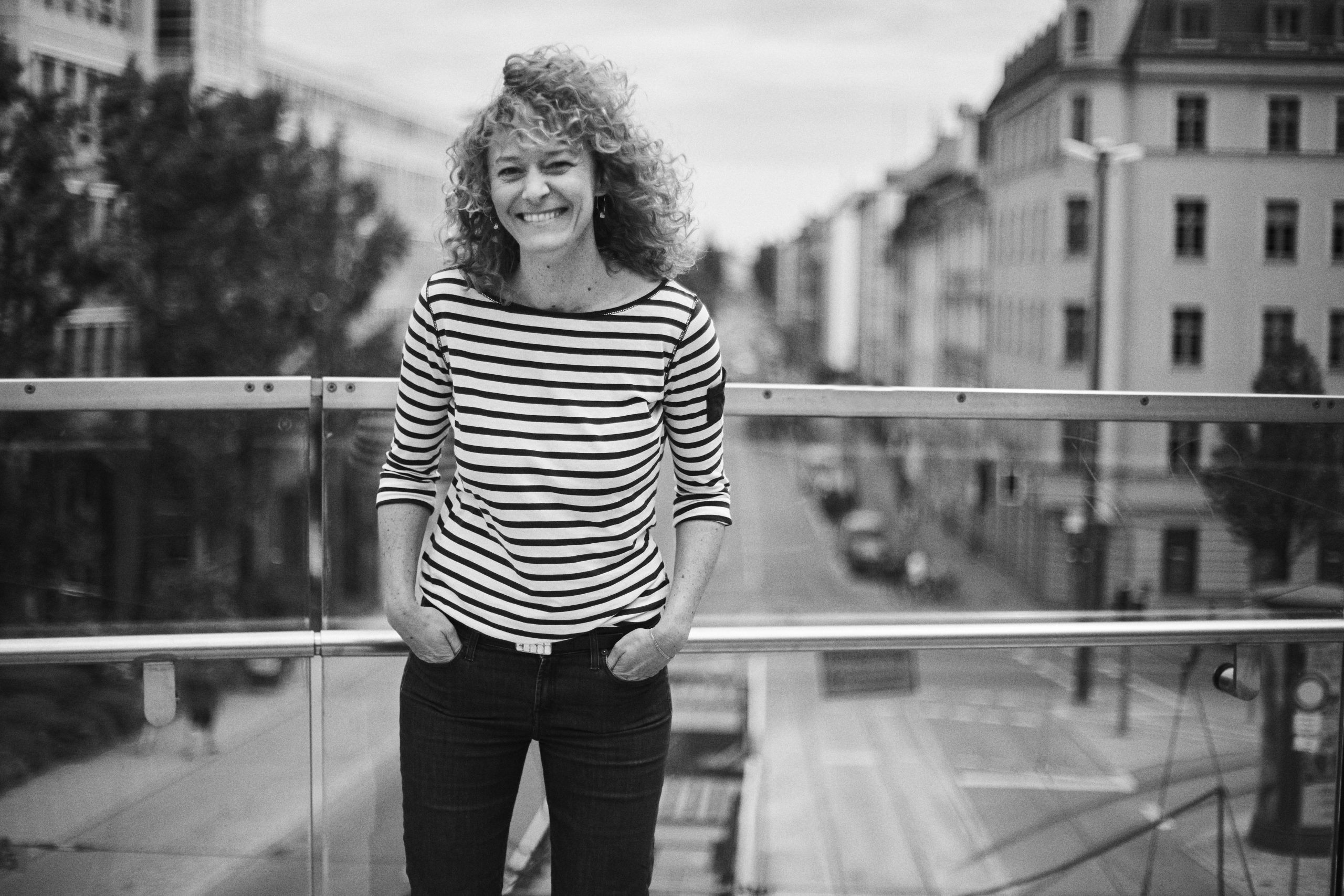 Vicky Breskott steht lachend auf einer Brücke mit München im Hintergrund.