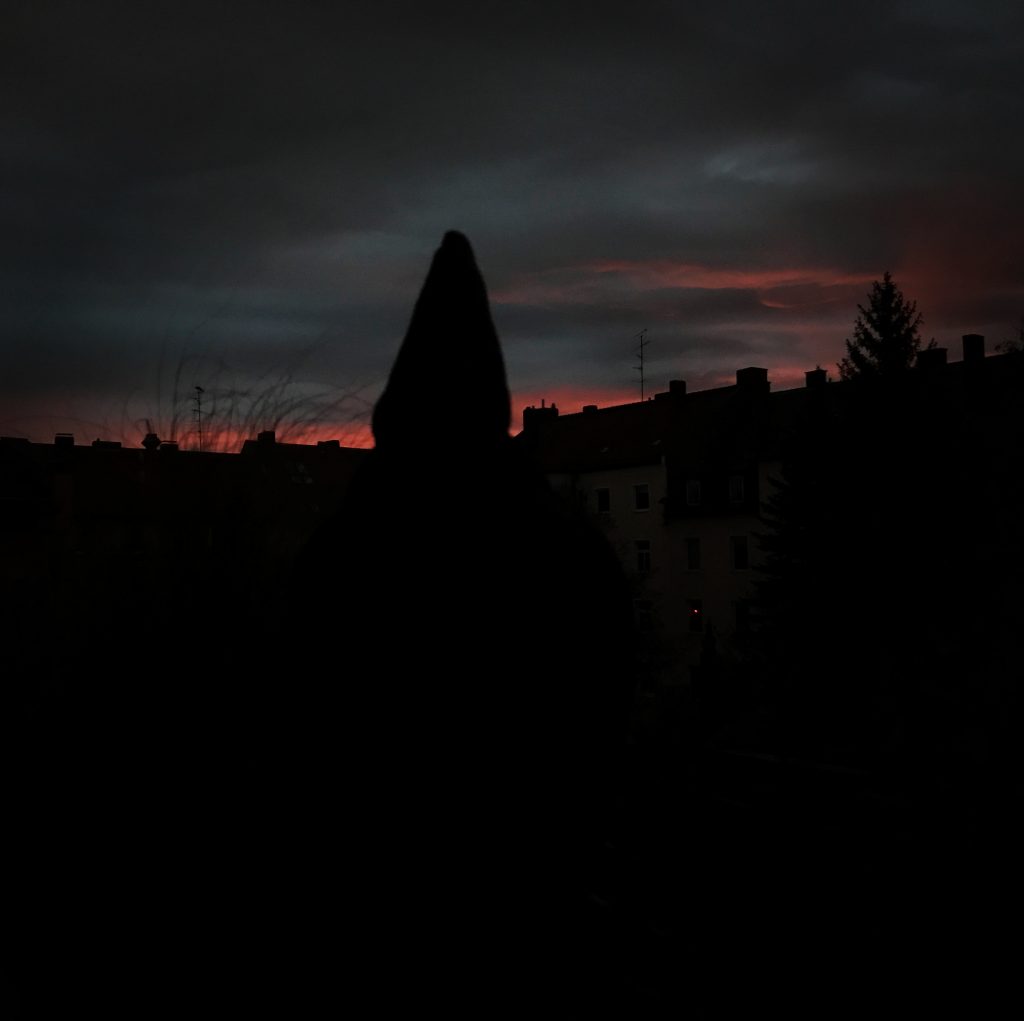 Blick von einem Balkon mit Buddha-Statue in eine bewölkte Abenddämmerung.