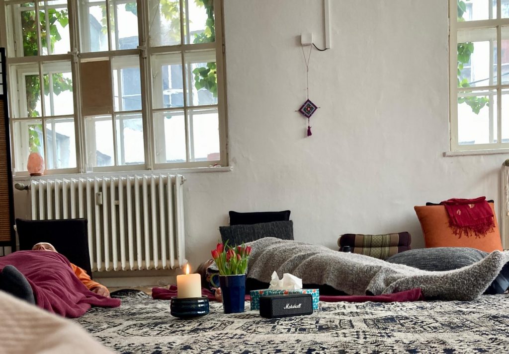 Teilnehmende eines Stimmseminars liegen während einer Meditation.